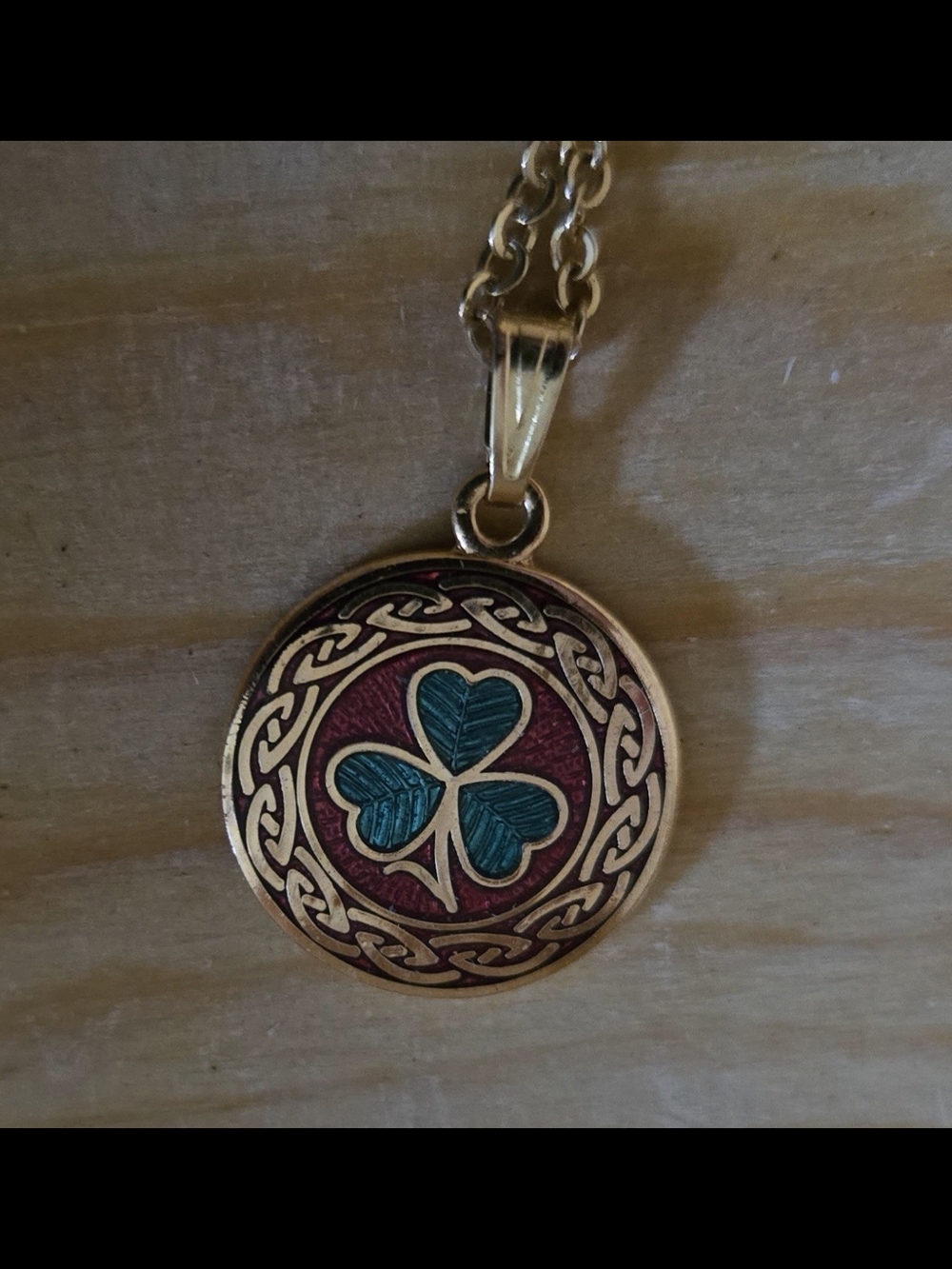 Gold-Tone Clover Pendant Necklace with Teal Enamel on Red Background